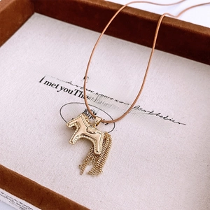 Detailed close-up of golden horse pendant with delicate chain tassels on display tray