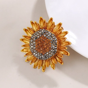 Detailed close-up of golden sunflower brooch with orange and grey rhinestones