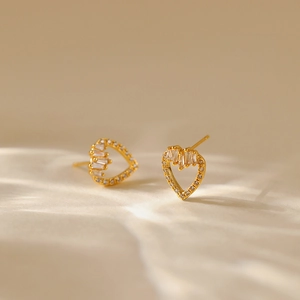 Macro shot of gold-plated leaf earrings with sparkling cubic zirconia on beige fabric