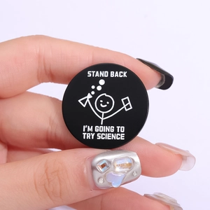 Black enamel science badge with text Stand Back I am Going to Try Science on hand