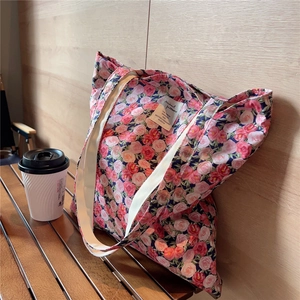 Close-up of vintage pink floral canvas tote bag featuring rose pattern and woven strap