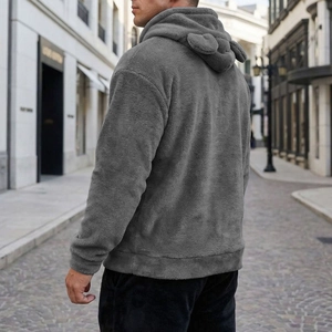 Rear view of a grey plush hoodie with cute animal ears on the hood in a street setting