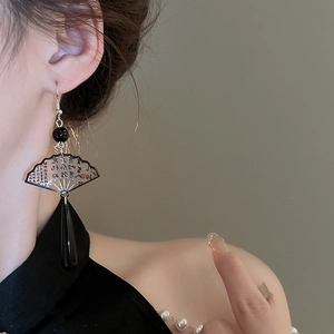 Detail of vintage Chinese resin fan earring with black teardrop charm on female model