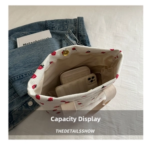 Interior view showing corduroy tote bag capacity with strawberry print and magnetic snap