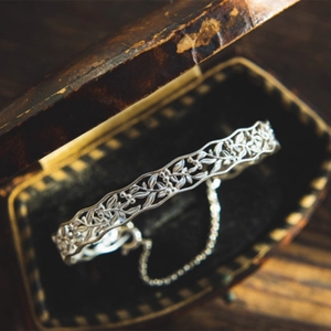 Detailed view of silver hollow leaf pattern bracelet with safety chain in vintage box