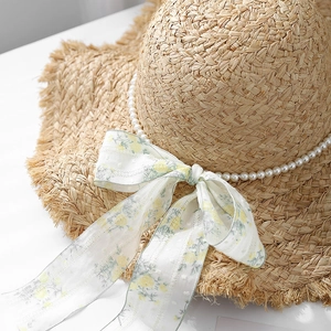 Cappello di paglia con fiocco in pizzo, catena di perle e tesa sfrangiata da spiaggia
