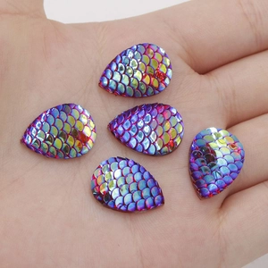 Macro view of 13x18mm teardrop resin scales with iridescent AB finish on a palm