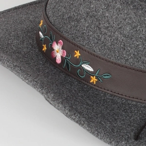 Macro shot of dark grey wool felt fedora with detailed floral embroidery on a brown band