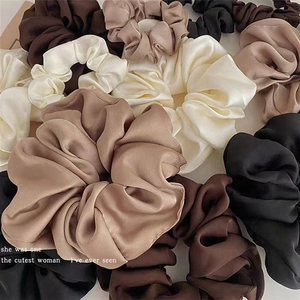 Stack of elegant satin scrunchies in earth tones like mocha and cream for ponytails