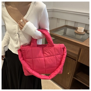 Close-up of rose red quilted puffer bag with fabric texture and padded handles