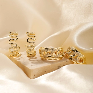 Polished gold U-shaped wavy earrings and zircon chain rings on champagne silk