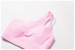 Detail of pink one-shoulder sports bra with asymmetric straps and wide supportive band