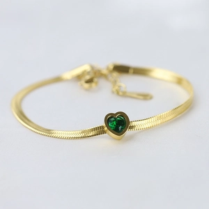 Close-up of a 14K gold stainless steel snake chain bracelet with a green heart crystal