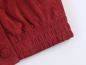 Detail of red faux suede jacket hem with elastic cuff and matching fabric buttons