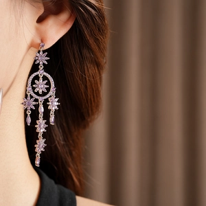 Detail of purple zircon flower tassel earrings worn by a model in soft lighting