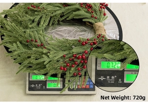 Macro view of Christmas wreath detailing red berries, green needles, and burlap ribbon