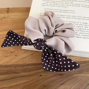Detailed texture of lavender scrunchie and brown polka dot bow on a wooden table