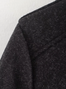 Detailed macro view of black wool-blend fabric texture and stitching on the collar
