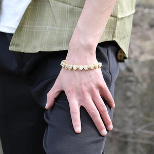 Dettaglio di un bracciale dorato con cuori in zircone indossato sul polso di una modella