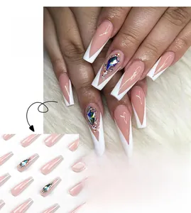 Detailed view of French tip press-on nails with nude pink base and colorful rhinestones