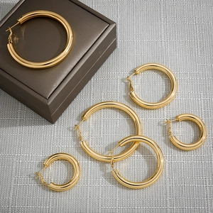 Three sizes of polished 18K gold plated stainless steel hoop earrings on gray fabric