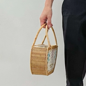 Detail of hand-woven rattan handbag featuring floral fabric side panels and sturdy handles