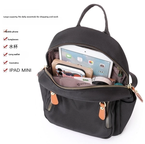 Detail view of the black nylon backpack showing large storage capacity with daily items
