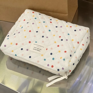 Detail view of quilted cotton cosmetic bag featuring colorful polka dots and zip closure