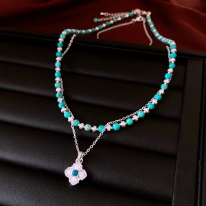 Detail of vintage flower zircon pendant with turquoise beads on a black leather display