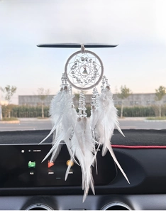 Close-up of a white dreamcatcher car pendant with feathers and crystal beads on rearview mirror
