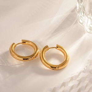 Close-up of double layer gold stainless steel hoop earrings on a decorative glass tray