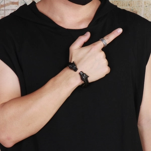 Close-up of a men's punk black twin wolf head open bangle and silver textured ring