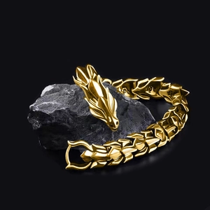 Detail of golden dragon head bracelet on dark rock showcasing punk style craftsmanship