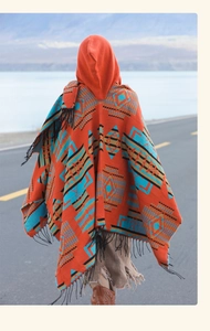 Outdoor shot of an oversized orange tribal poncho with tassels and geometric patterns