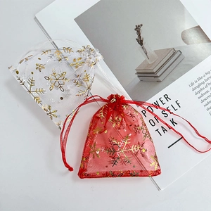 Detail of red and white organza gift bags with gold snowflake pattern on a book