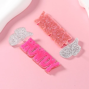 Macro shot of pink HOWDY letters and silver cowboy hat glittery acrylic earrings