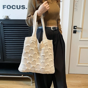 Close-up of cream knit tote bag showing the unique 3D wavy texture and wide handle