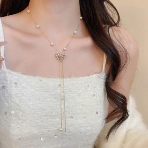 Close-up of elegant 18k gold plated Y-necklace with pearls and crystal bow detail