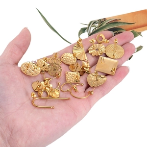 Golden stainless steel geometric heart and floral earrings displayed in hand
