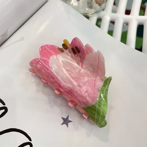 Pink and green floral acrylic claw clip with pearlescent finish on magazine background