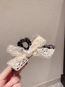 Détail d'une pince à cheveux à nœud en dentelle florale avec perle crème et tissu rétro