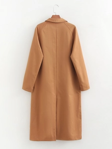 Detail view of camel long trench coat back side with split hem design on a hanger