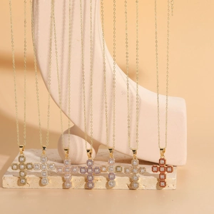 Close-up of 14K gold plated necklaces featuring colorful cross pendants on stone base