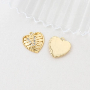 Detailed macro view of 14k gold plated heart pendants with inlaid cubic zirconia accents