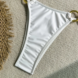 Gros plan d'un bas de bikini blanc avec anneau métallique doré et coutures précises