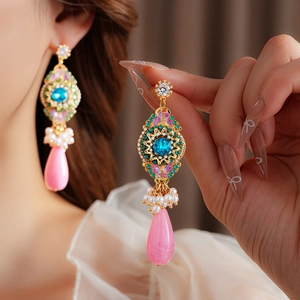 Gros plan de boucles d'oreilles vintage en or avec zircon, perles et gemme rose en goutte
