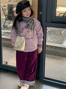 Mädchen präsentiert modisches Outfit mit bedrucktem Sweatshirt und Cordhose