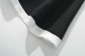 Detail of black twill fabric dress with elegant white contrast binding and fine stitching