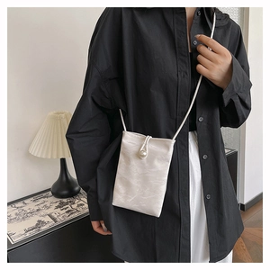 Détail du mini sac de téléphone en tissu moiré blanc avec fermoir perle et fine bandoulière