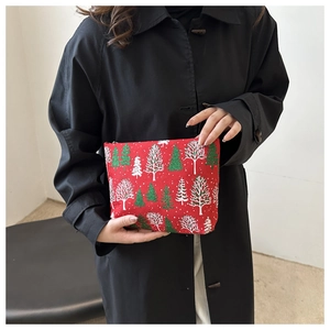 Detail of red festive toiletry bag with pine tree patterns held by a model